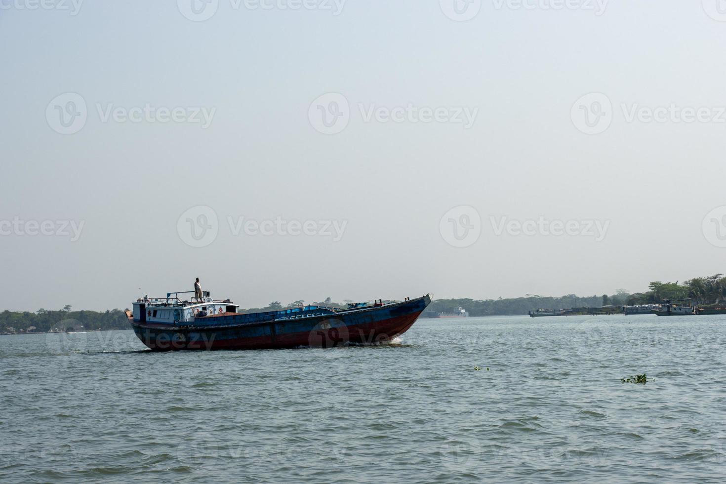 Troller boat on the river delivering goods close-up photo. Beautiful rural area and water vessel transportation. Beautiful sky and river horizon scenery with a motorboat. Restless river and blue sky. photo