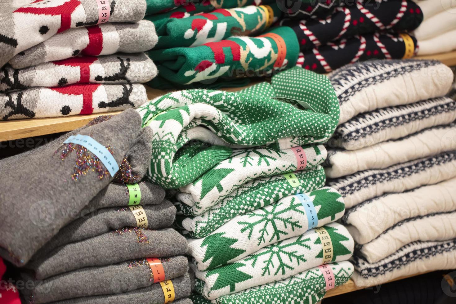 Sweaters with Christmas ornaments in the store.Stack of folded knitted photo
