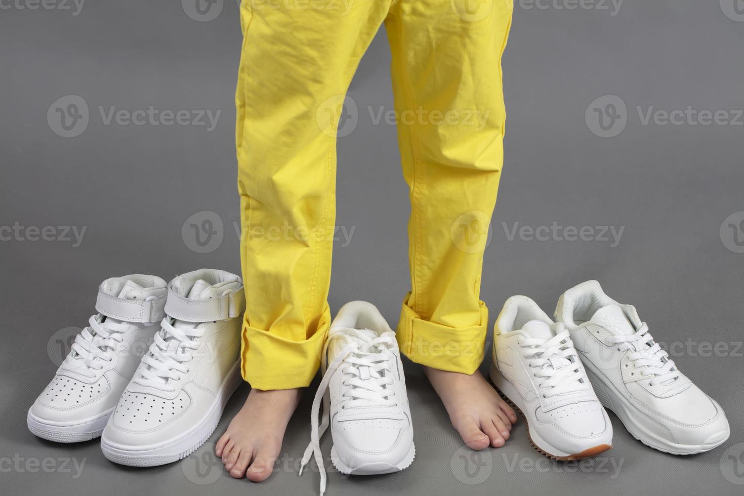 Barefoot on the background of shoes. Feet in a pile of shoes. Children's foot on the background of sneakers. Foot and shoes photo