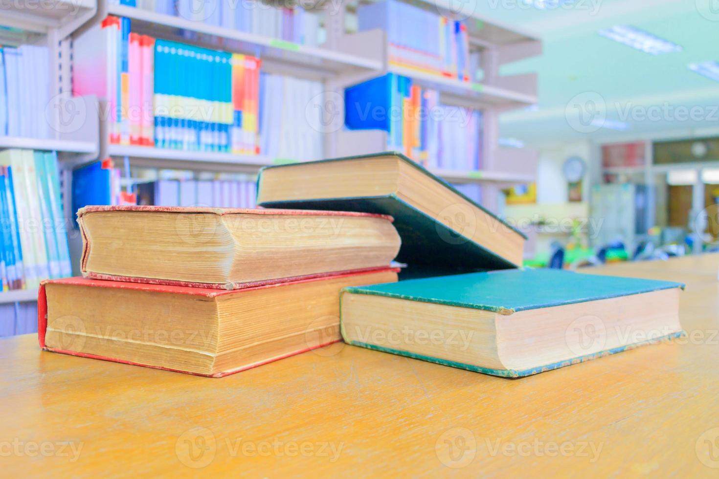 old book red - green. and heap treatise in school library on wooden table.  blurry bookshelves background. education learning concept with copy space add text photo