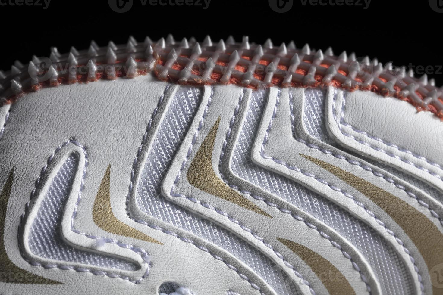 Part of a white sneaker with a sole on a dark background. Macro fragment of sports shoes photo