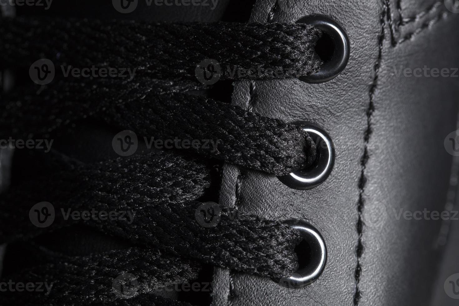 Part of a black boot with laces. A fragment of dark shoes. A piece of sneaker. photo