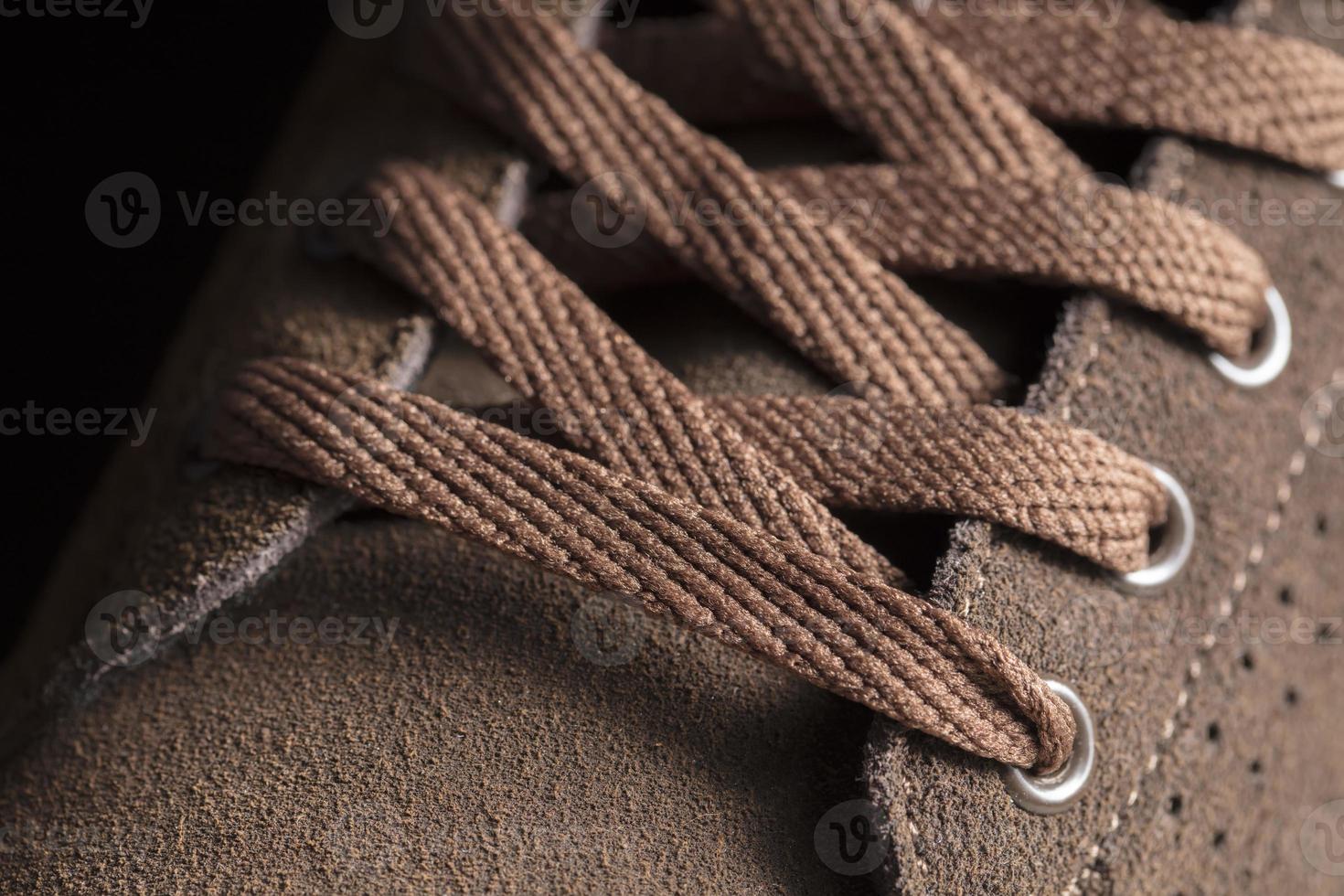 Part of a suede boot with laces. A fragment of brown shoes. A piece of sneaker. photo