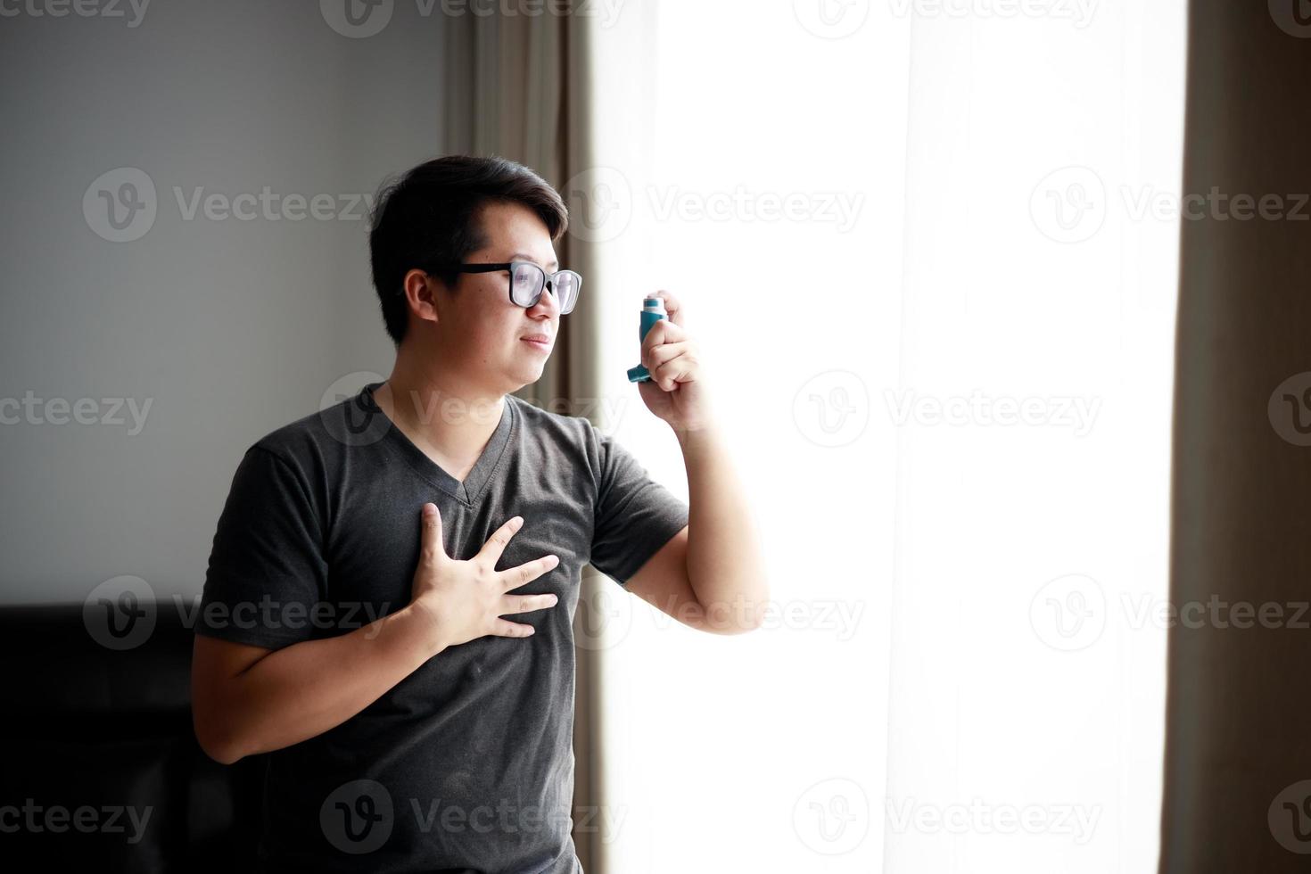 Sick Asian young man using nebulizer for asthma and respiratory diseases at home. photo