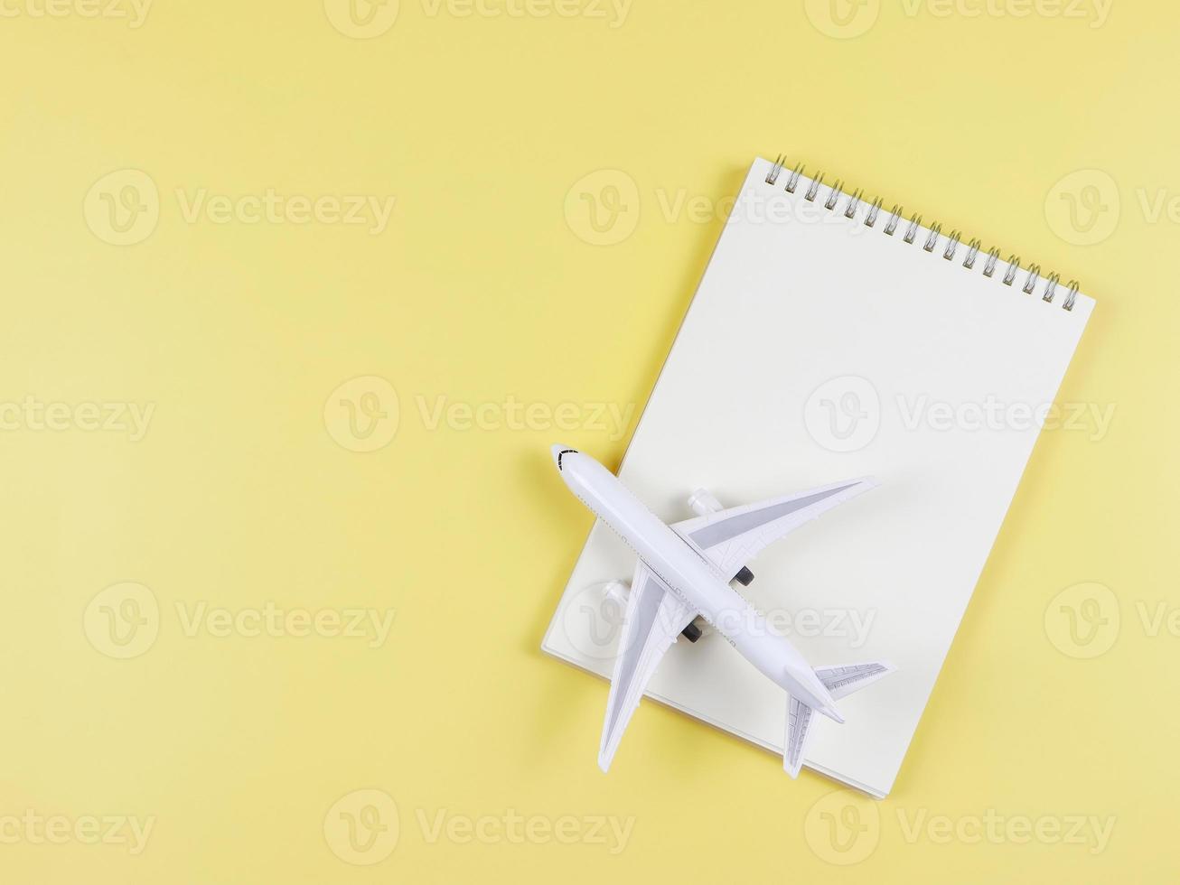 flat lay of blank page opened notebook, airplane model on yellow  background with copy space. Travel planning concept. photo