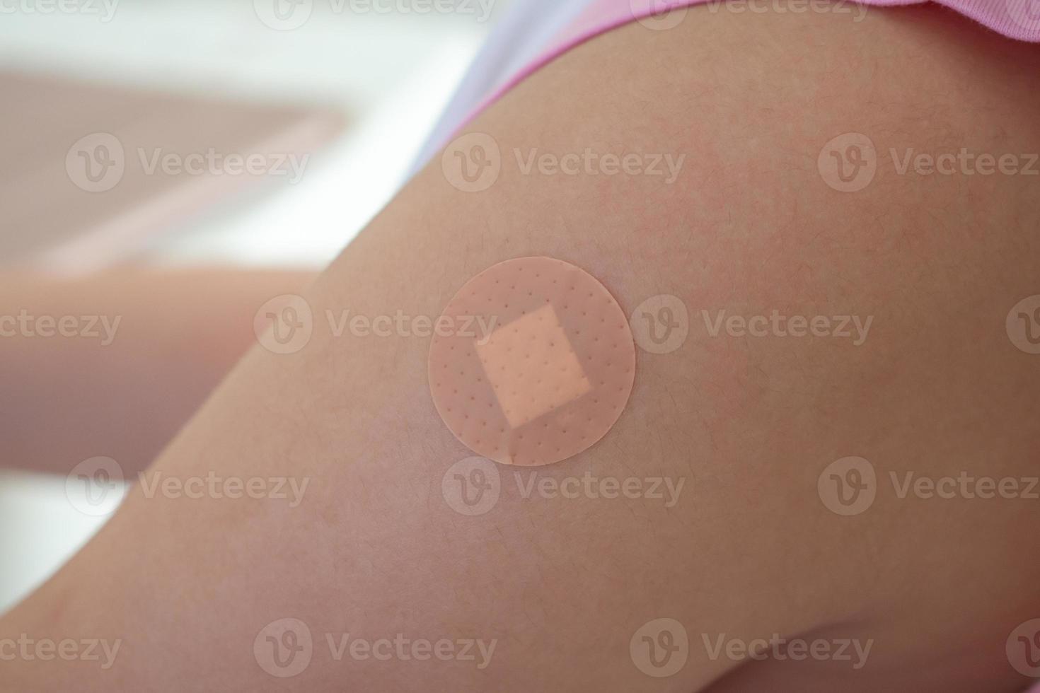 Vaccinated little asian girl with adhesive plaster after vaccine injection photo