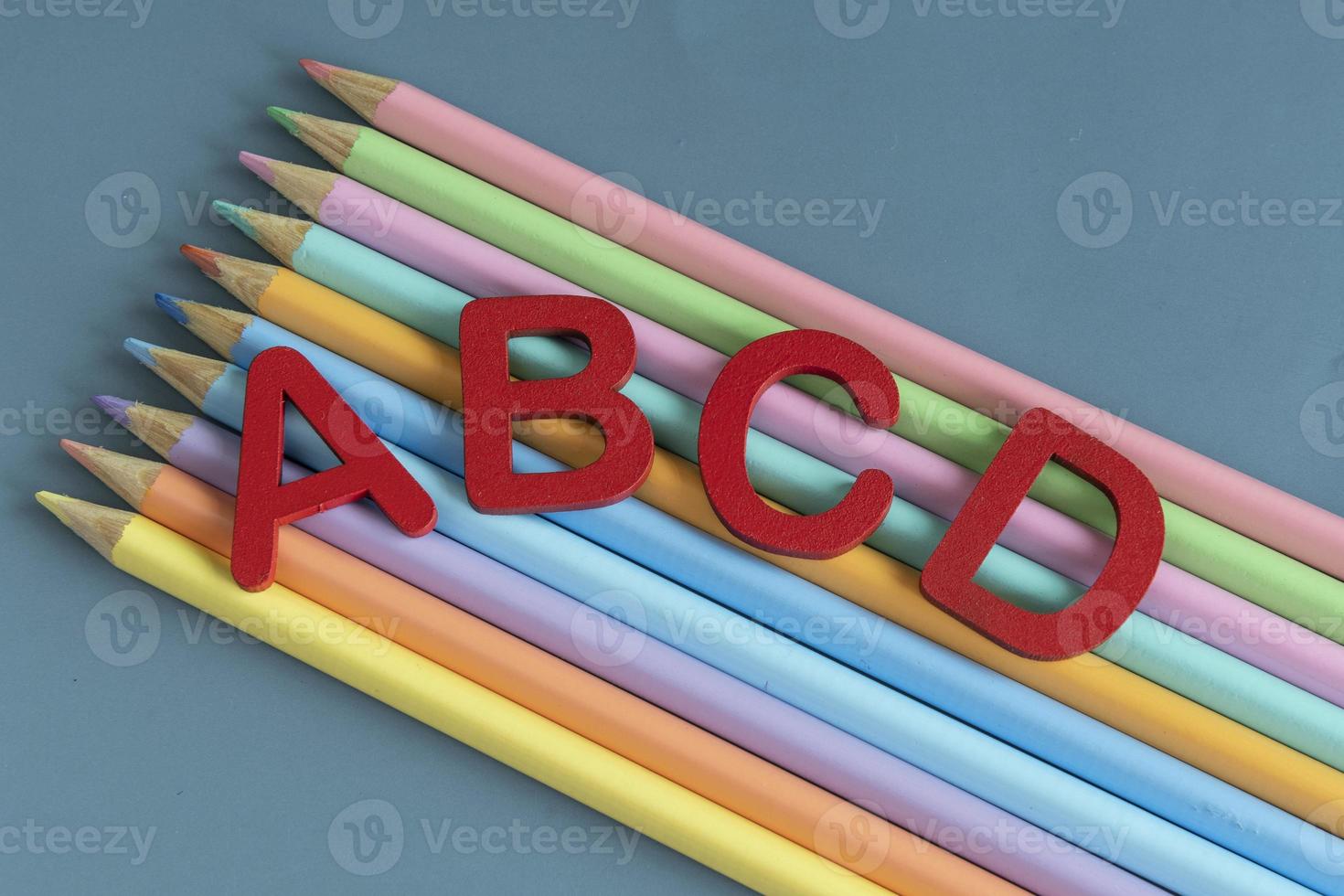 Back to school concept with assorted letters and colored pencils in pastel colors photo
