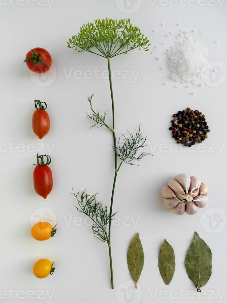 Ingredients for pickling red and yellow tomatoes. Concept culinary recipe preservation of vegetables in harvest season. Assorted tomatoes, garlic, dill, salt, pepper and bay leaf. Knolling concept. photo