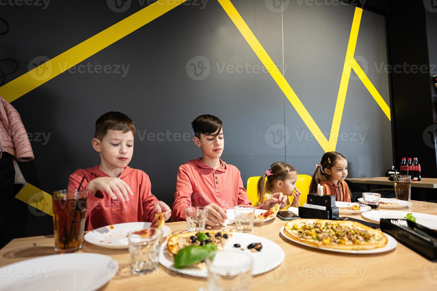 cuatro niños comiendo italiano Pizza en pizzería. niños comer a cafetería. foto