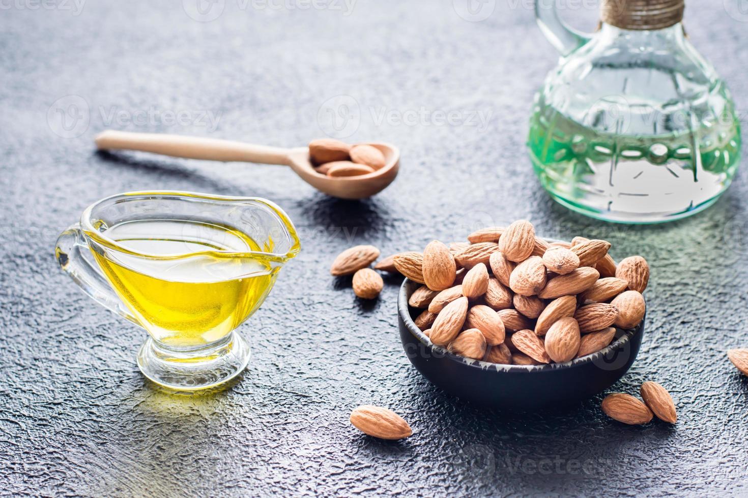 Fresh peeled almonds in a bowl and almond oil on the table. A source of vitamins and oils. Natural cosmetics photo