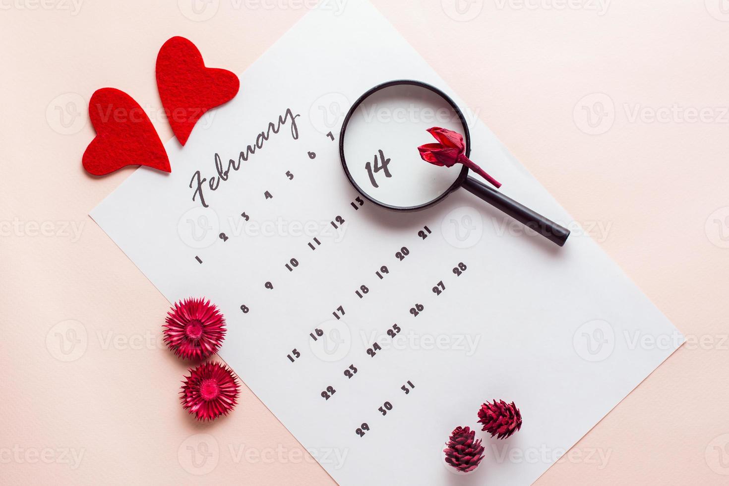 Valentine's Day. The magnifier highlights the date February 14 on the calendar sheet. Top view photo