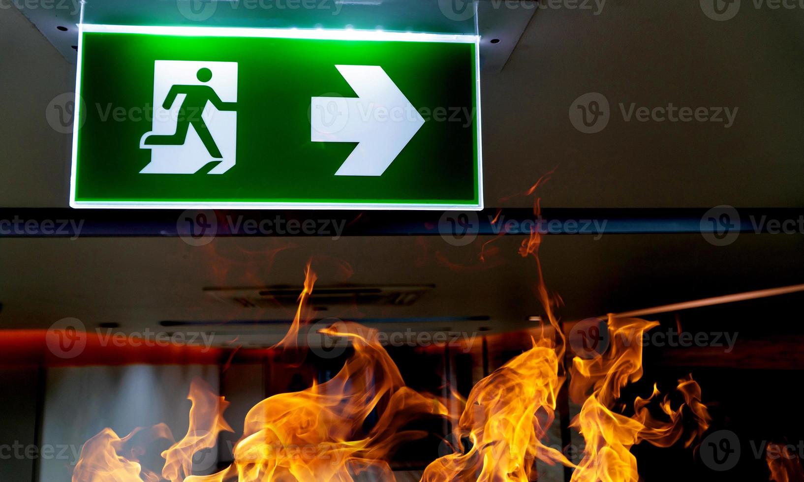Green fire escape sign hang on the ceiling in the office. photo