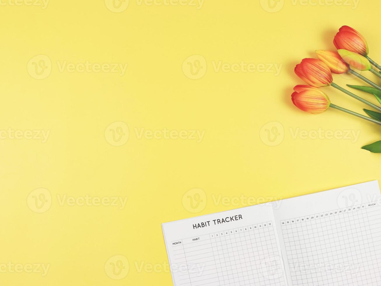 flat layout of Habit tracker book,  and tulips on yellow background. photo
