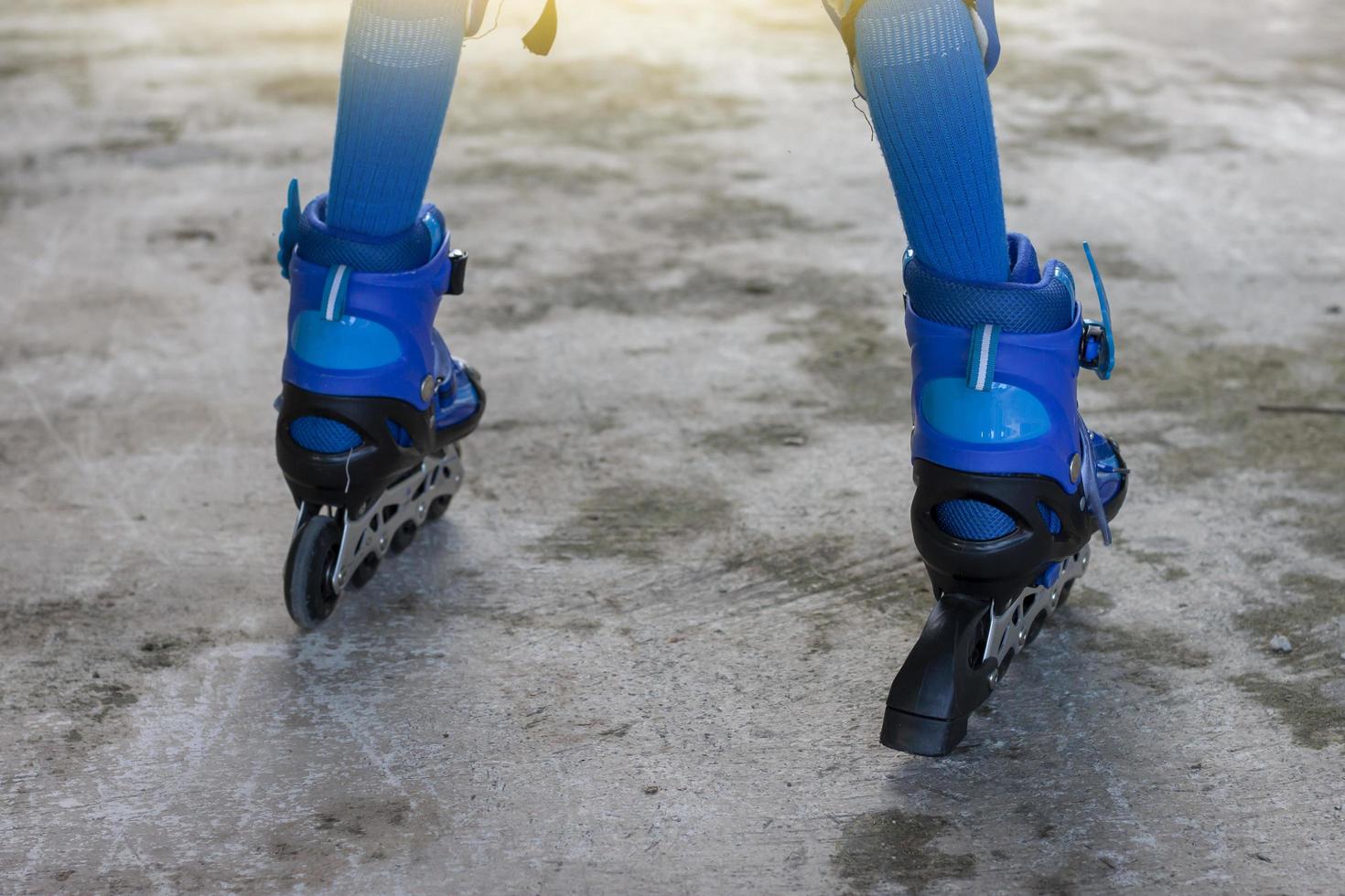 Little boy learning roller skate by wearing blue roller skate shoes on cement floor. photo