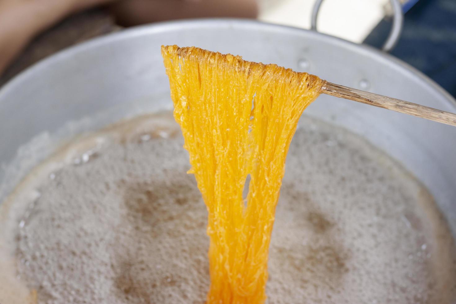Making Thai dessert Golden Egg yolk threads or Foi Thong in a pan with boiling syrup. photo