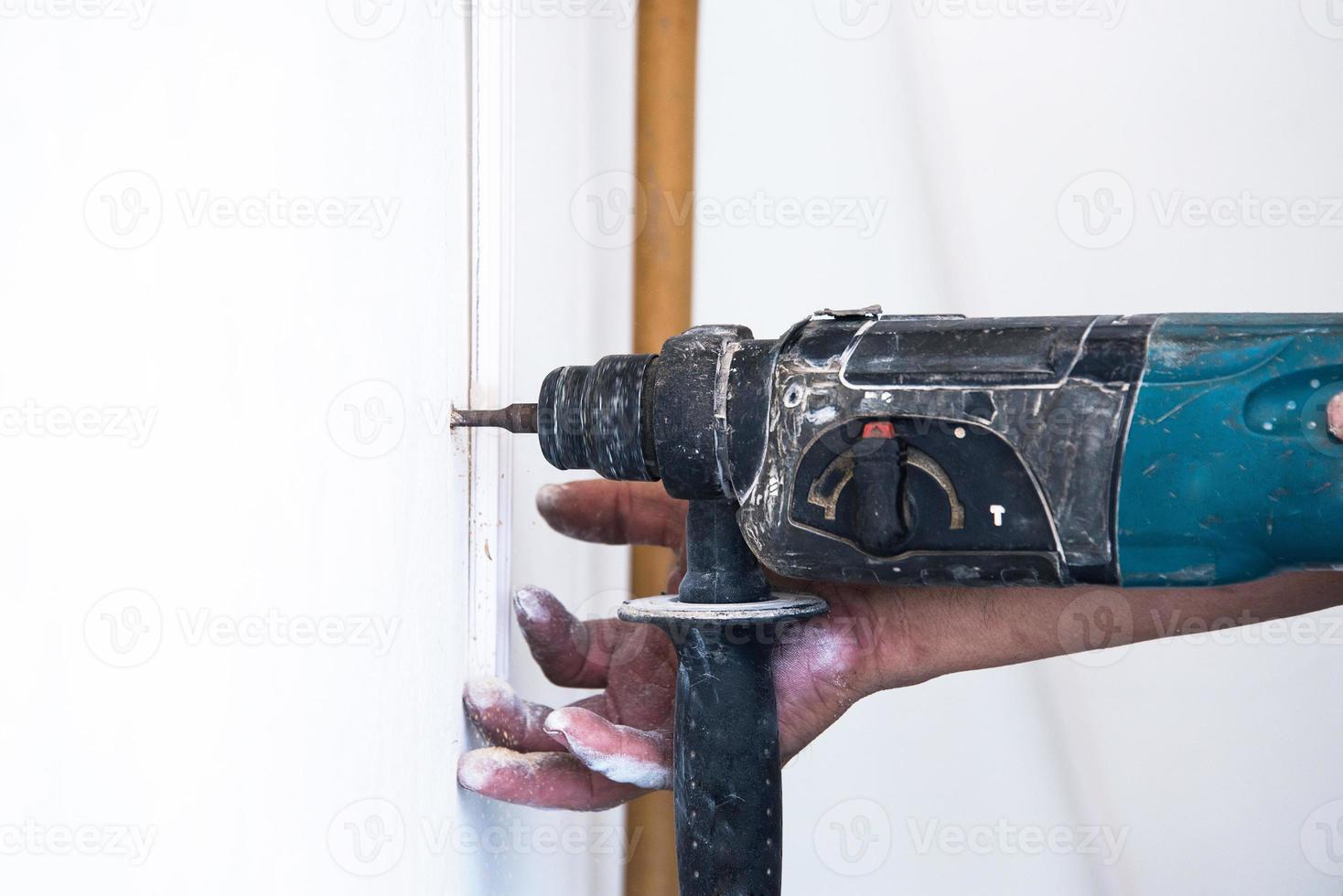 close up of electric drill making hole in a wall, repair, building and home concept photo