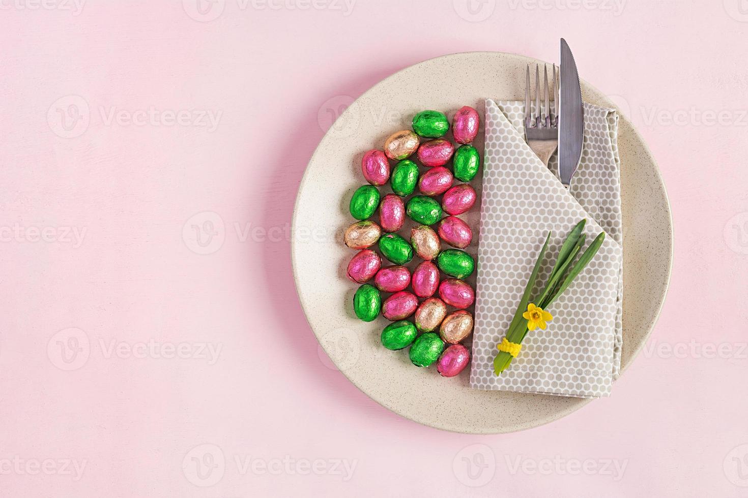 contento Pascua de Resurrección. mesa ajuste para Pascua de Resurrección día festivo. Pascua de Resurrección huevos, flor y cuchillería en rosado antecedentes. parte superior vista, plano laico foto