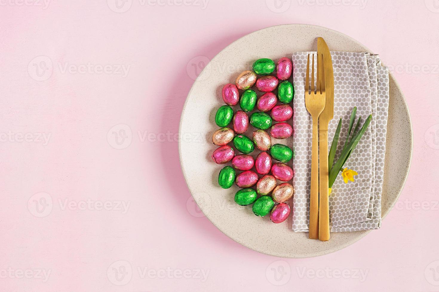 contento Pascua de Resurrección. mesa ajuste para Pascua de Resurrección día festivo. Pascua de Resurrección huevos, flor y cuchillería en rosado antecedentes. parte superior vista, plano laico foto