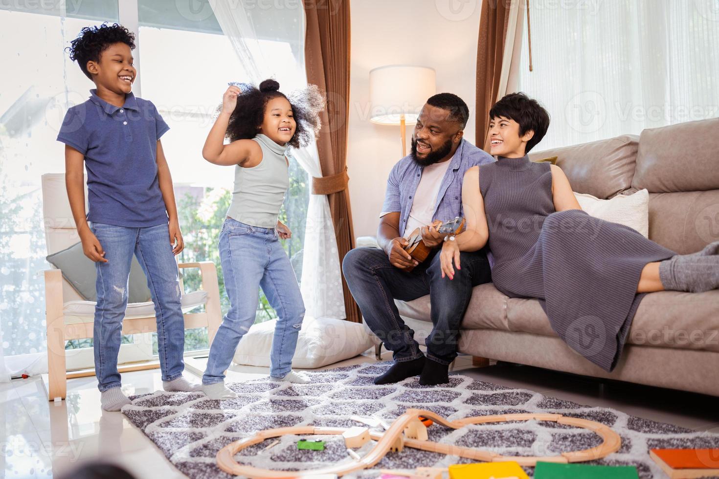 contento africano americano familia, hijo, hija, padres bailando juntos en vivo habitación foto