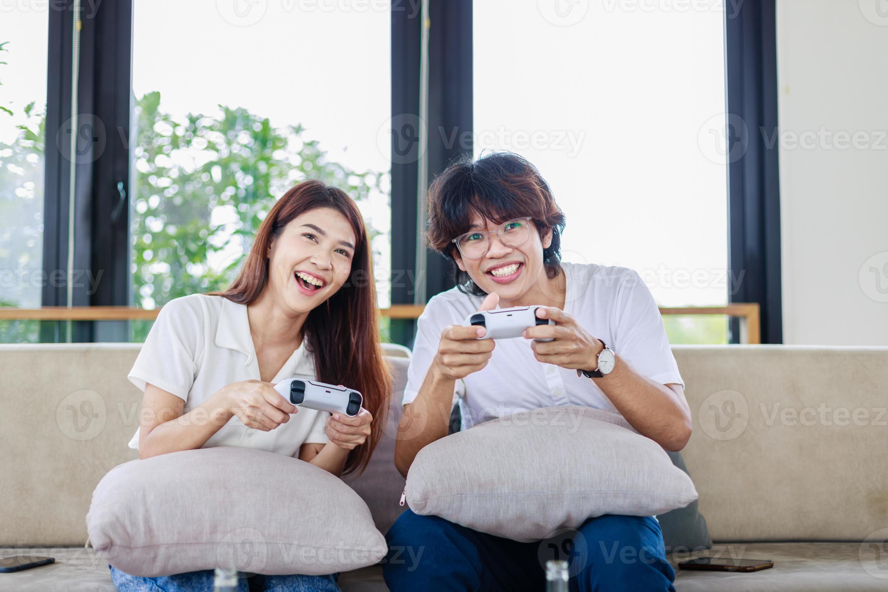 Happy Asian Couple Playing Computer Video Game Sitting On Couch At