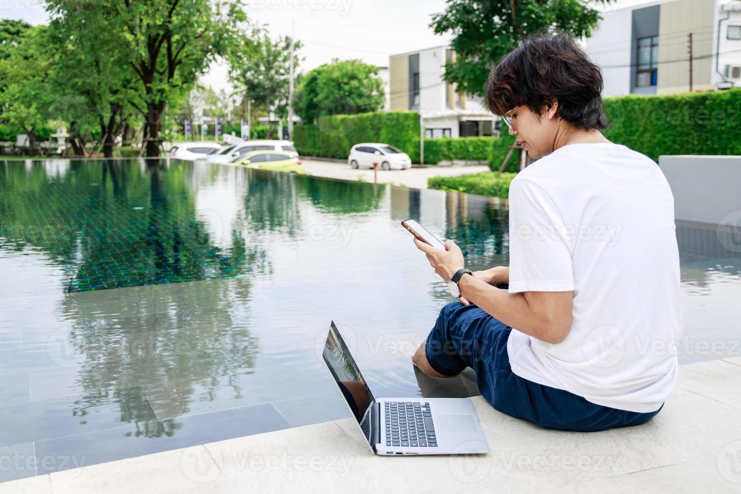 Businessman Balances Work and Leisure on Vacation by Poolside with Laptop photo