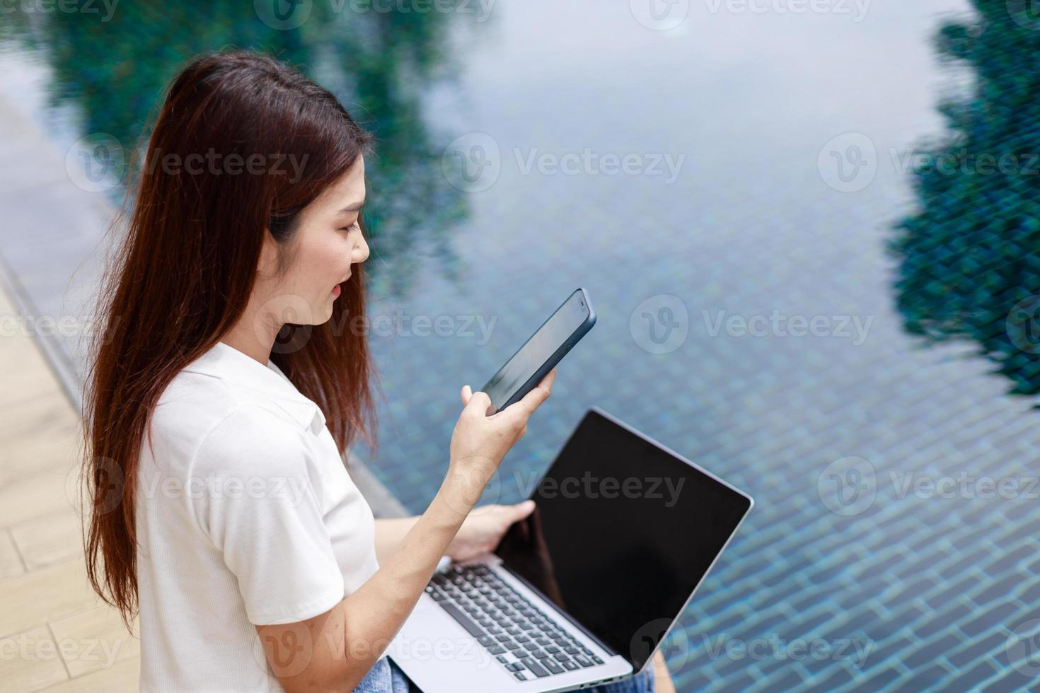 Woman Enjoys Vacation by the Pool with Smartphone in Hand at Resort Hotel photo