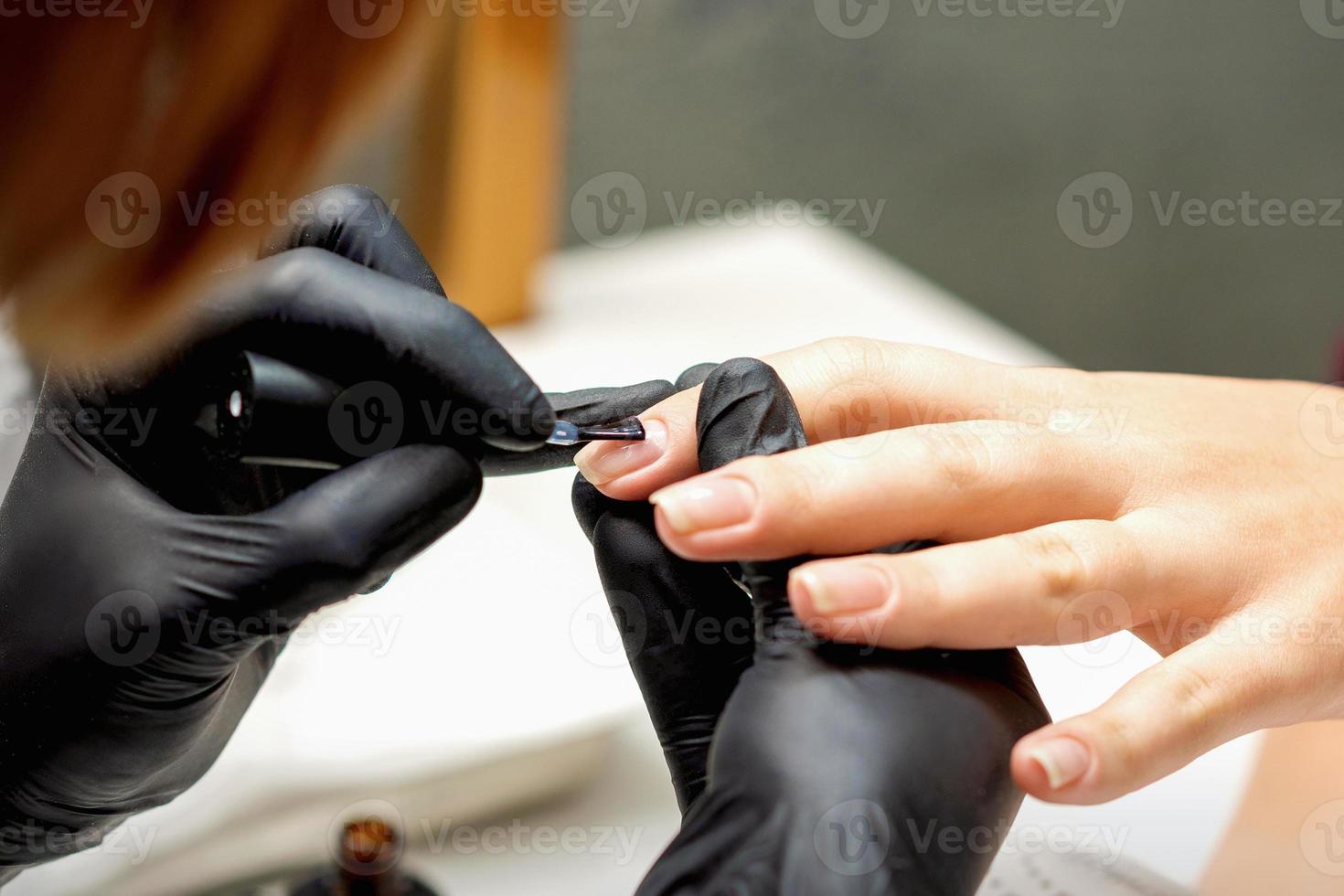 Master covering nails with transparent polish photo