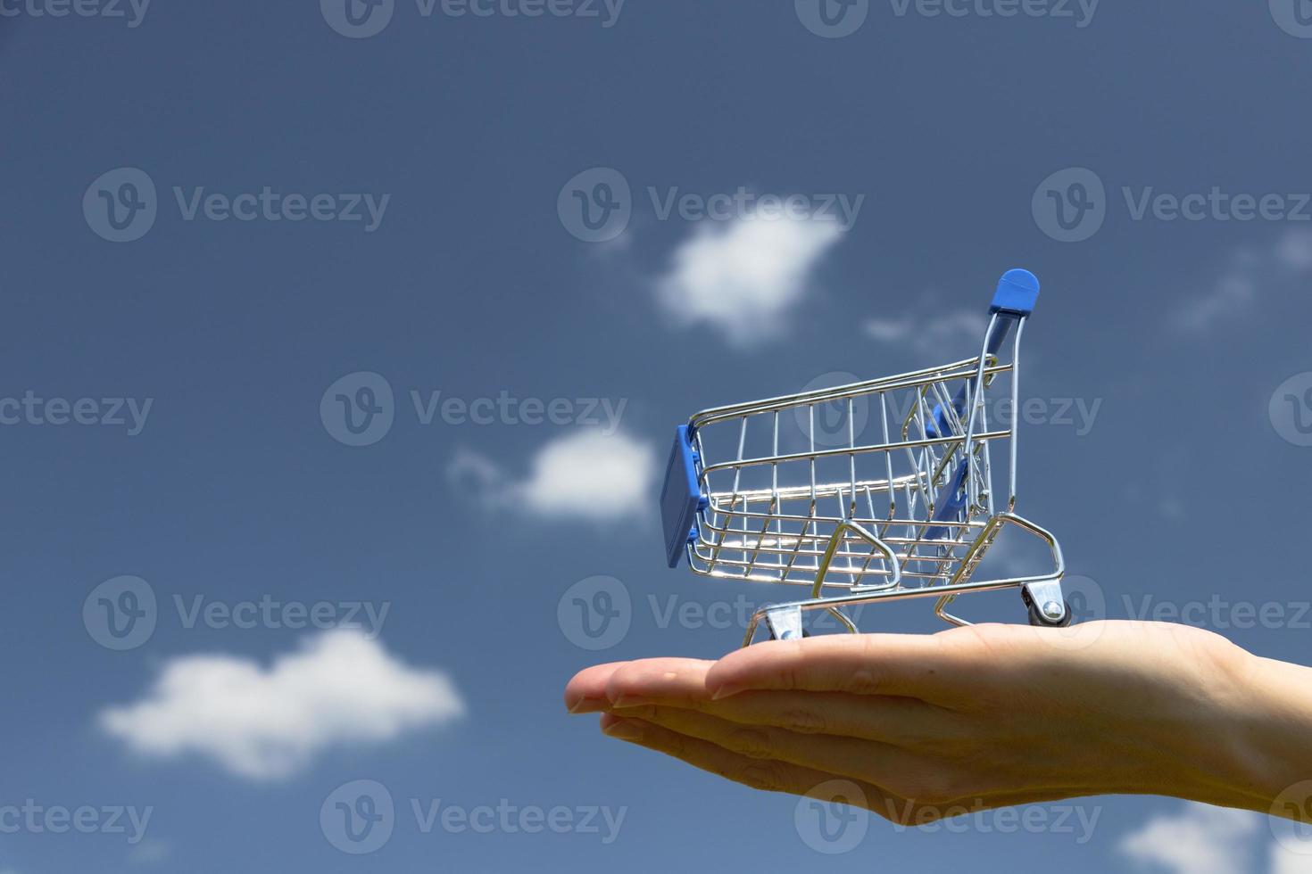 A supermarket trolley on a man's arm against the sky. Online shopping. photo