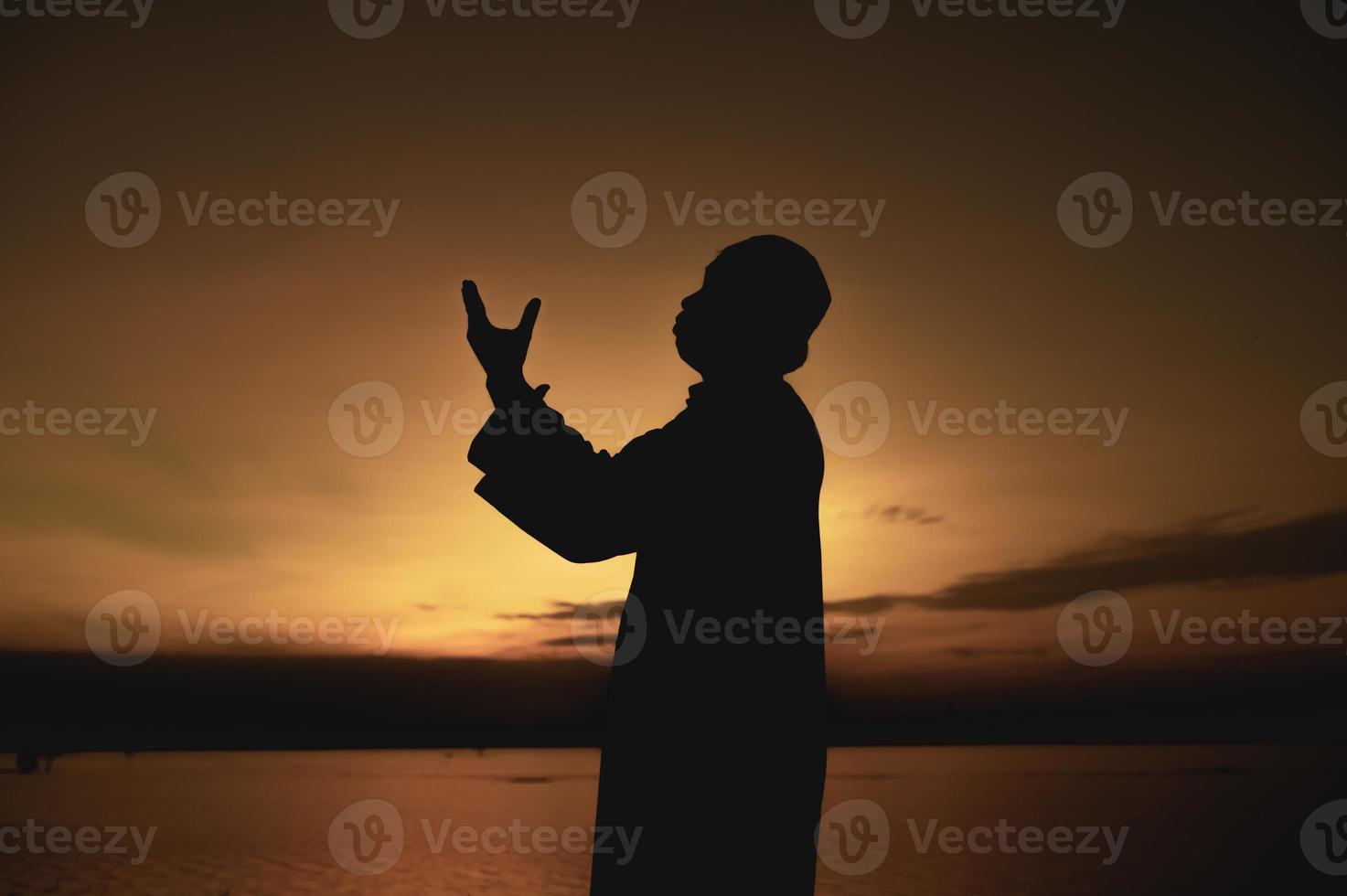 Silhouette Young asian muslim man praying on sunset,Ramadan festival concept photo