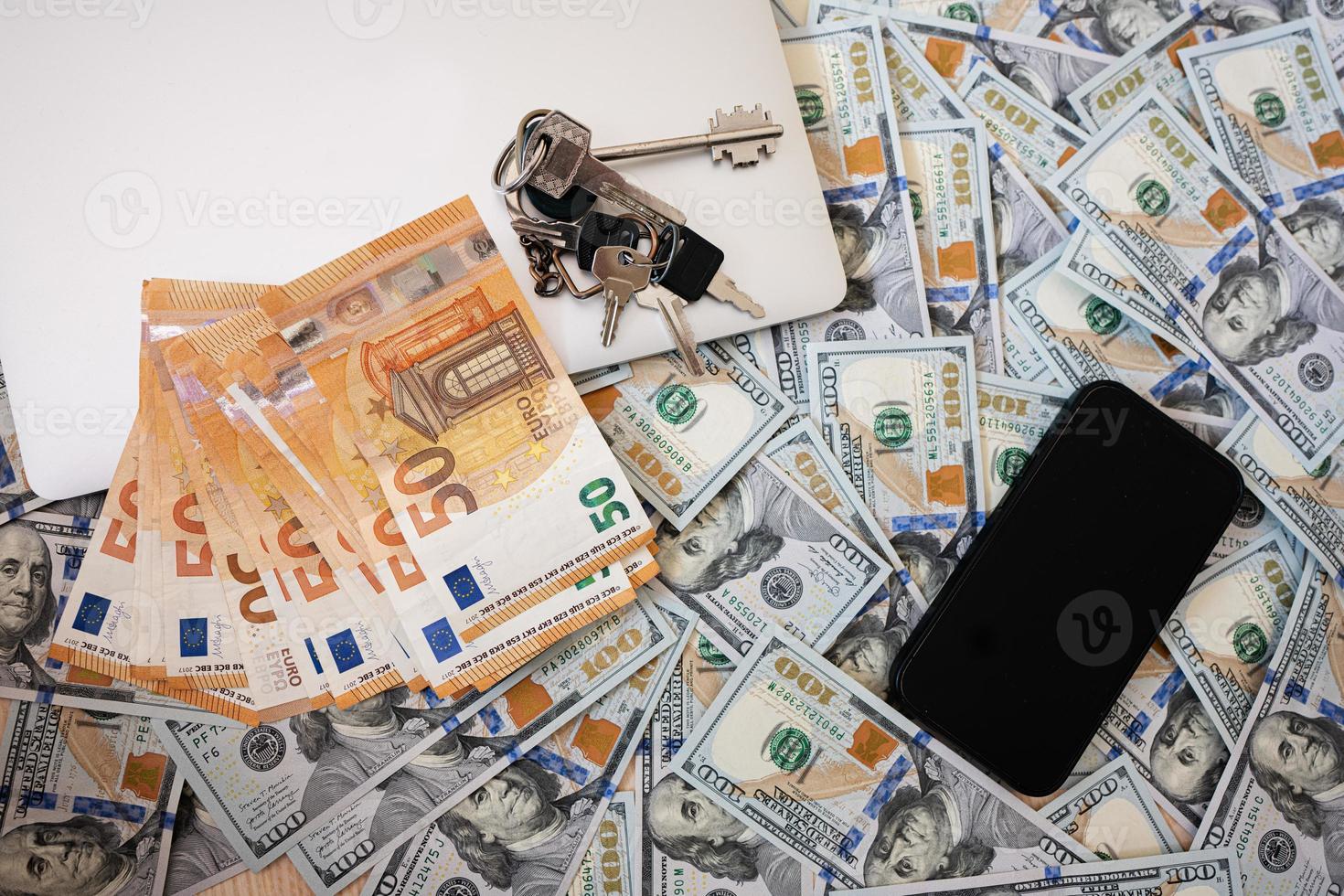 Dollar money with euro, keys, laptop and phone background. photo