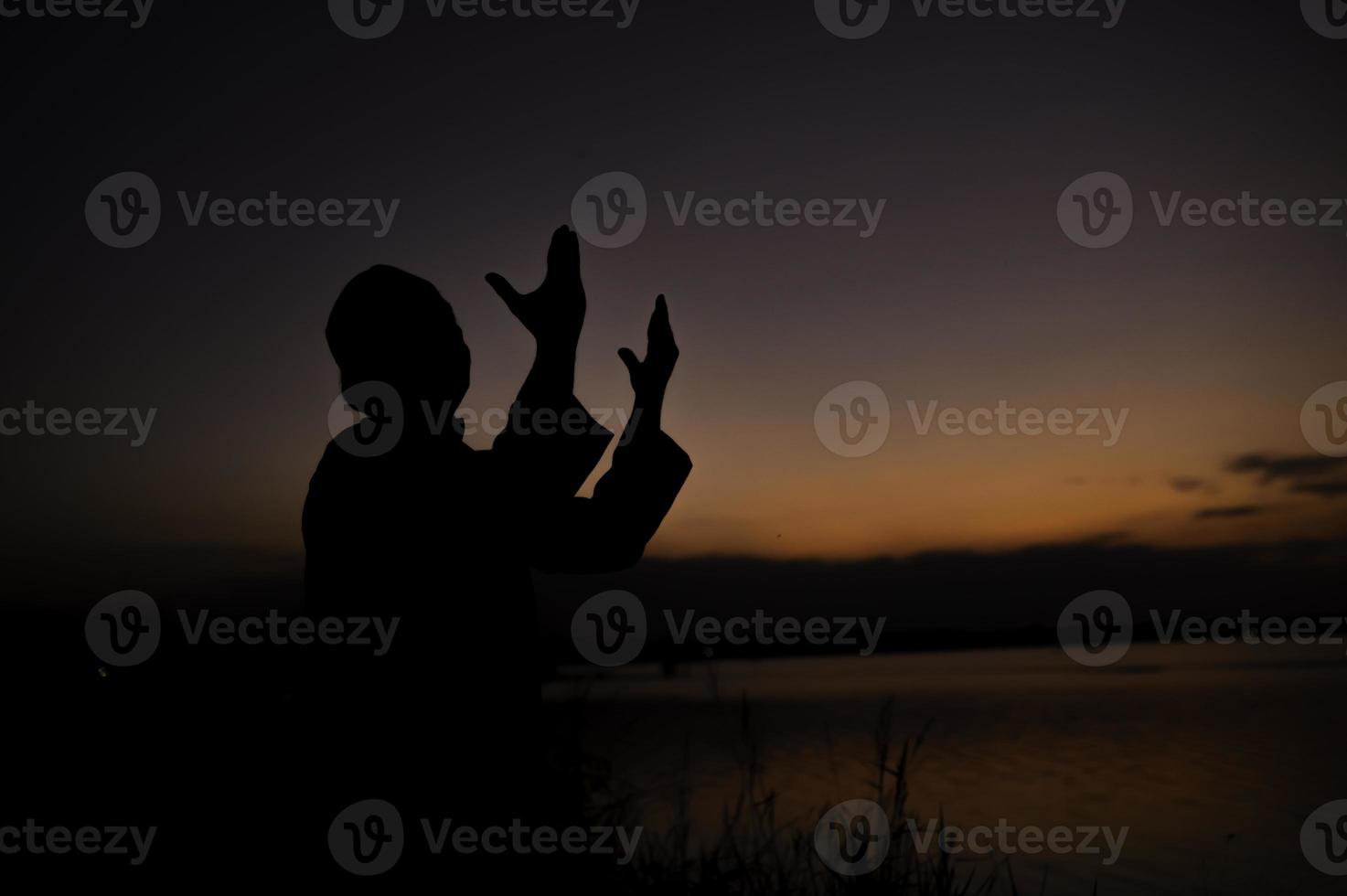 Silhouette Young asian muslim man praying on sunset,Ramadan festival concept photo