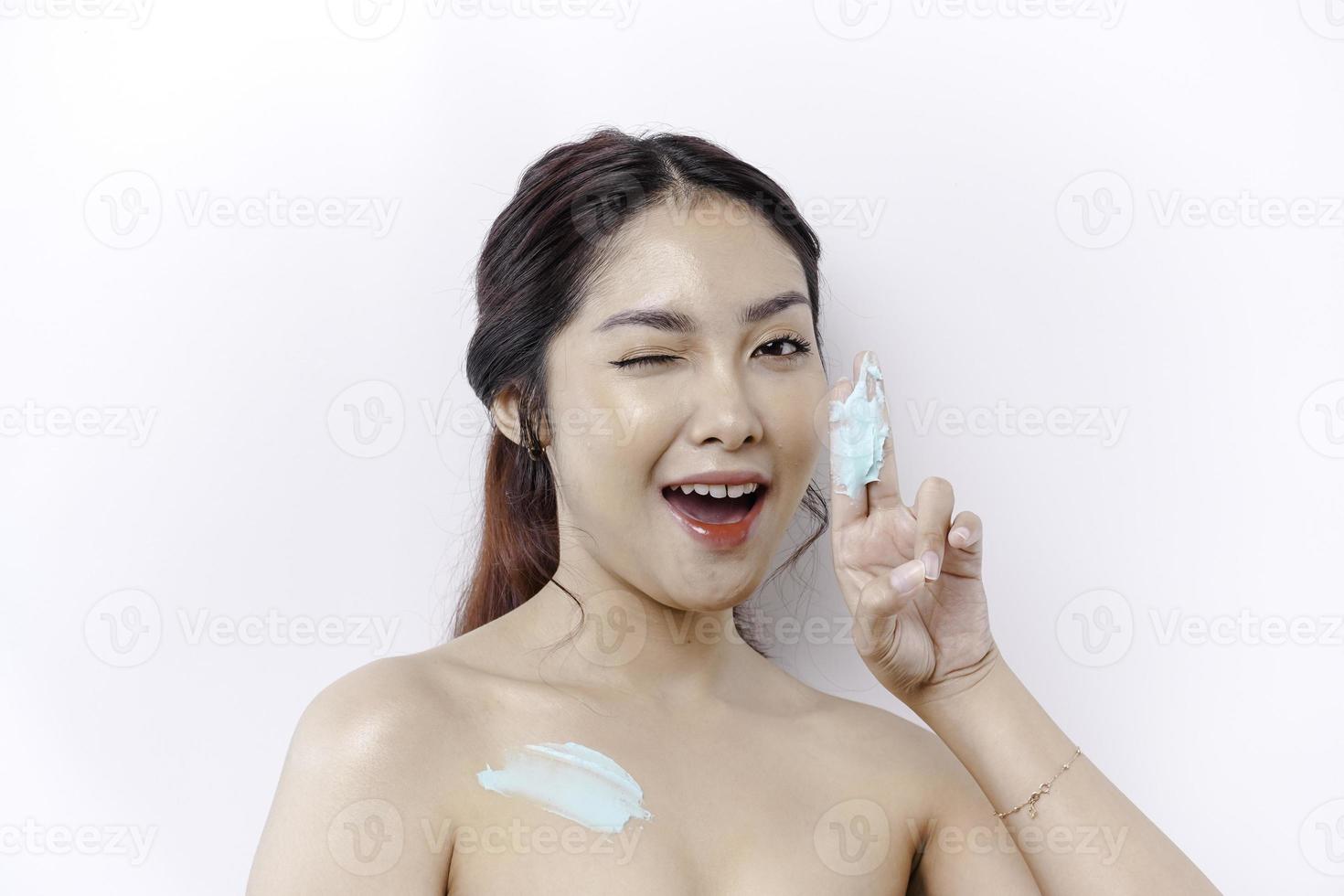 Skin Care Products Concept. Asian woman applying moisturizing lotion on body after shower, standing wrapped in towel, cropped image photo