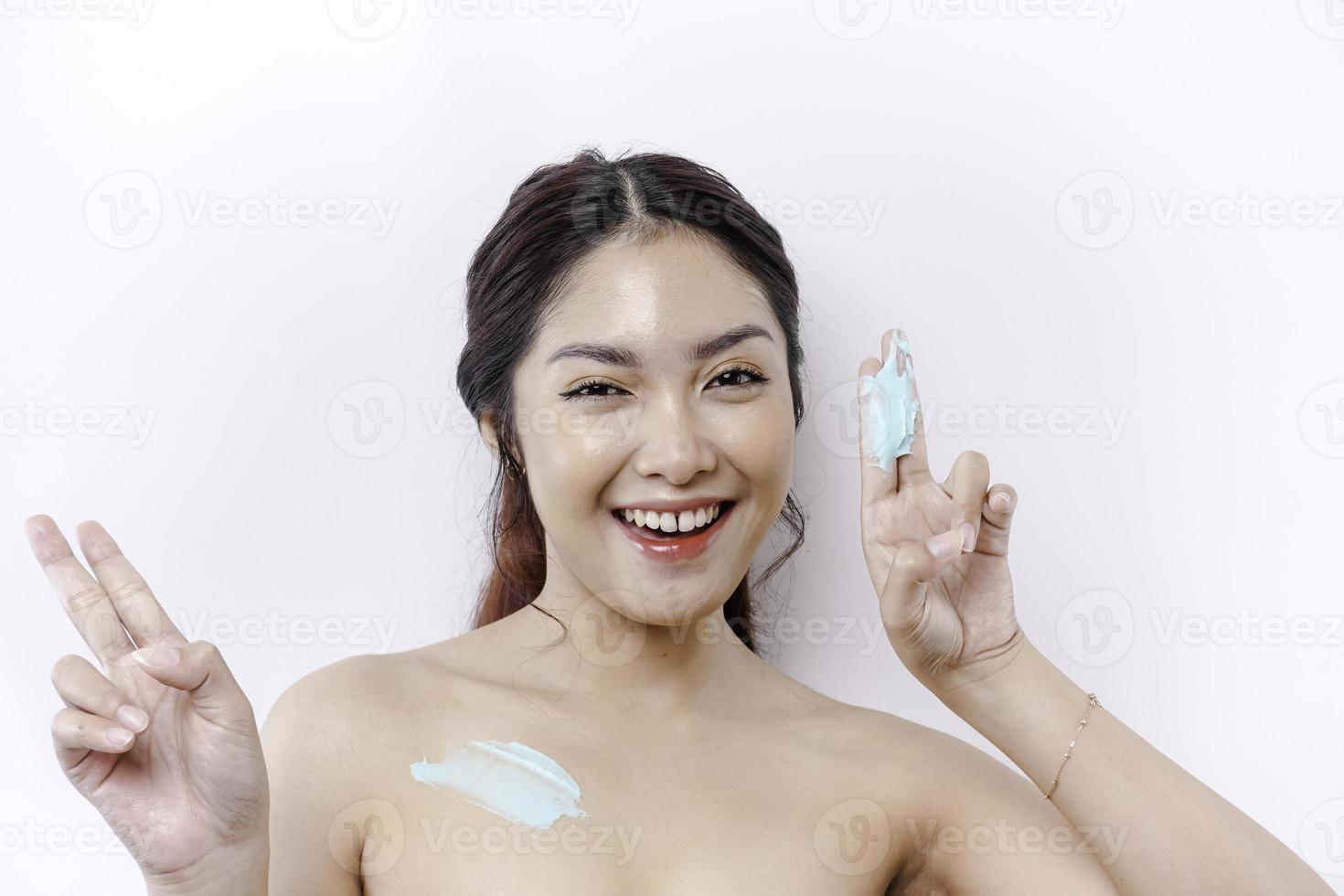 Skin Care Products Concept. Asian woman applying moisturizing lotion on body after shower, standing wrapped in towel, cropped image photo