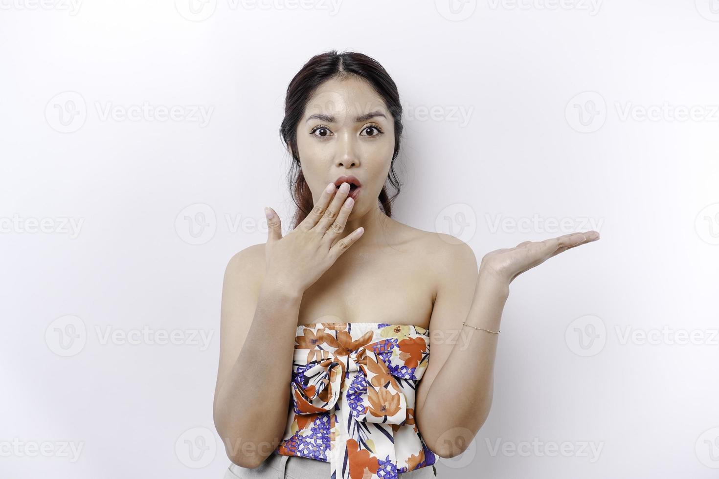 Shocked Asian woman pointing at the copy space on beside her, isolated by white background photo