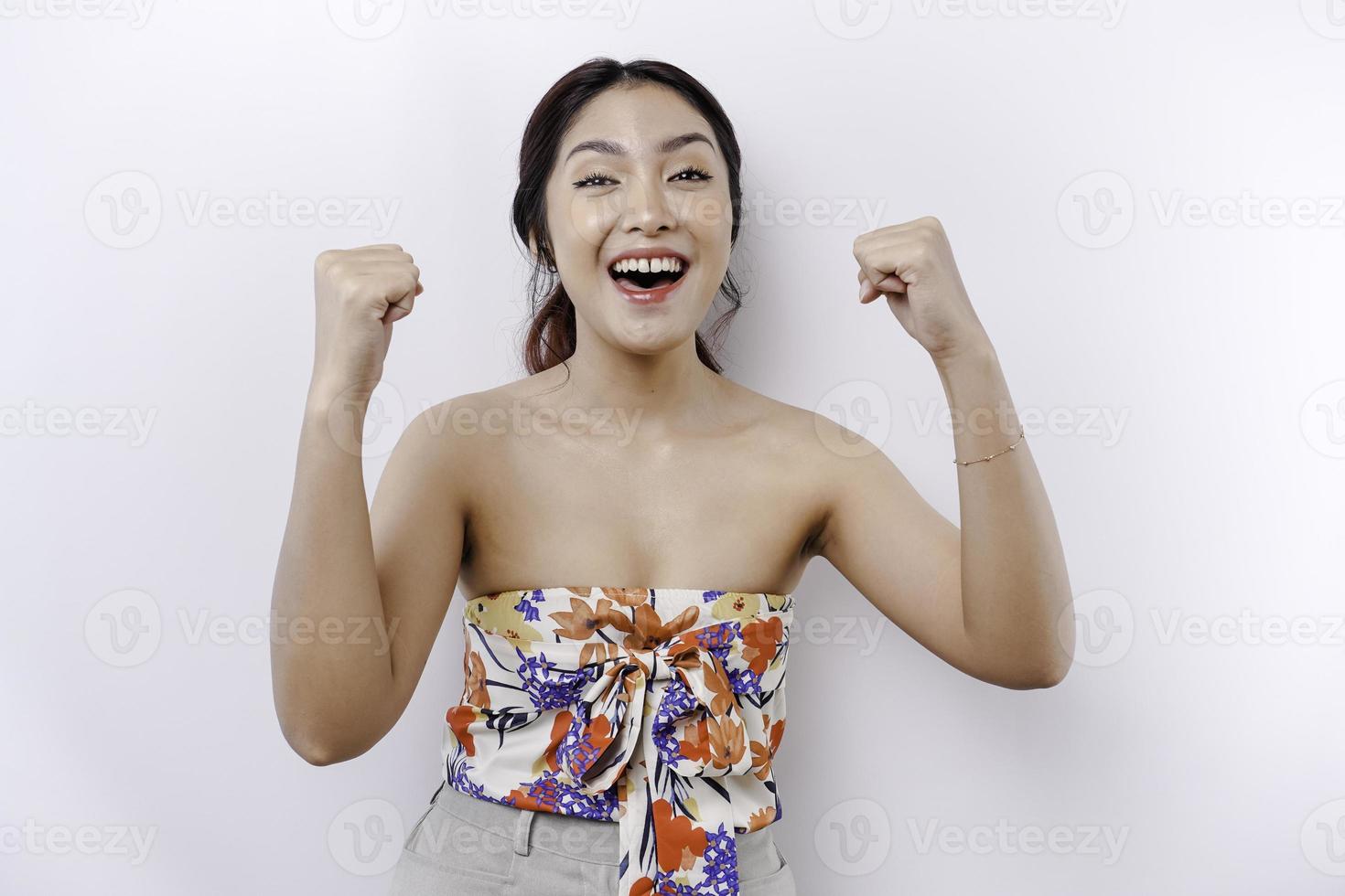 A young Asian woman with a happy successful expression wearing floral top isolated by white background photo