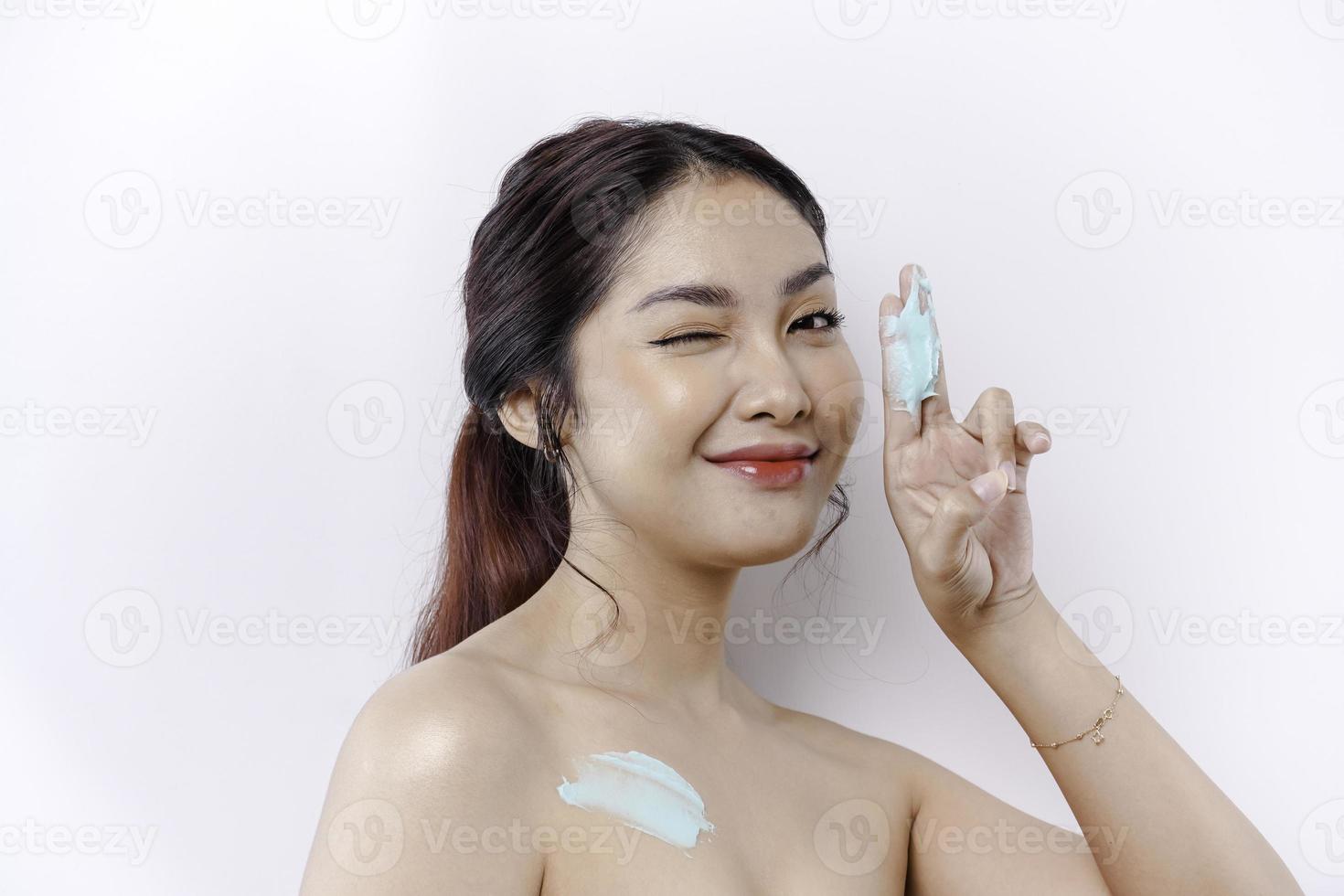 Skin Care Products Concept. Asian woman applying moisturizing lotion on body after shower, standing wrapped in towel, cropped image photo