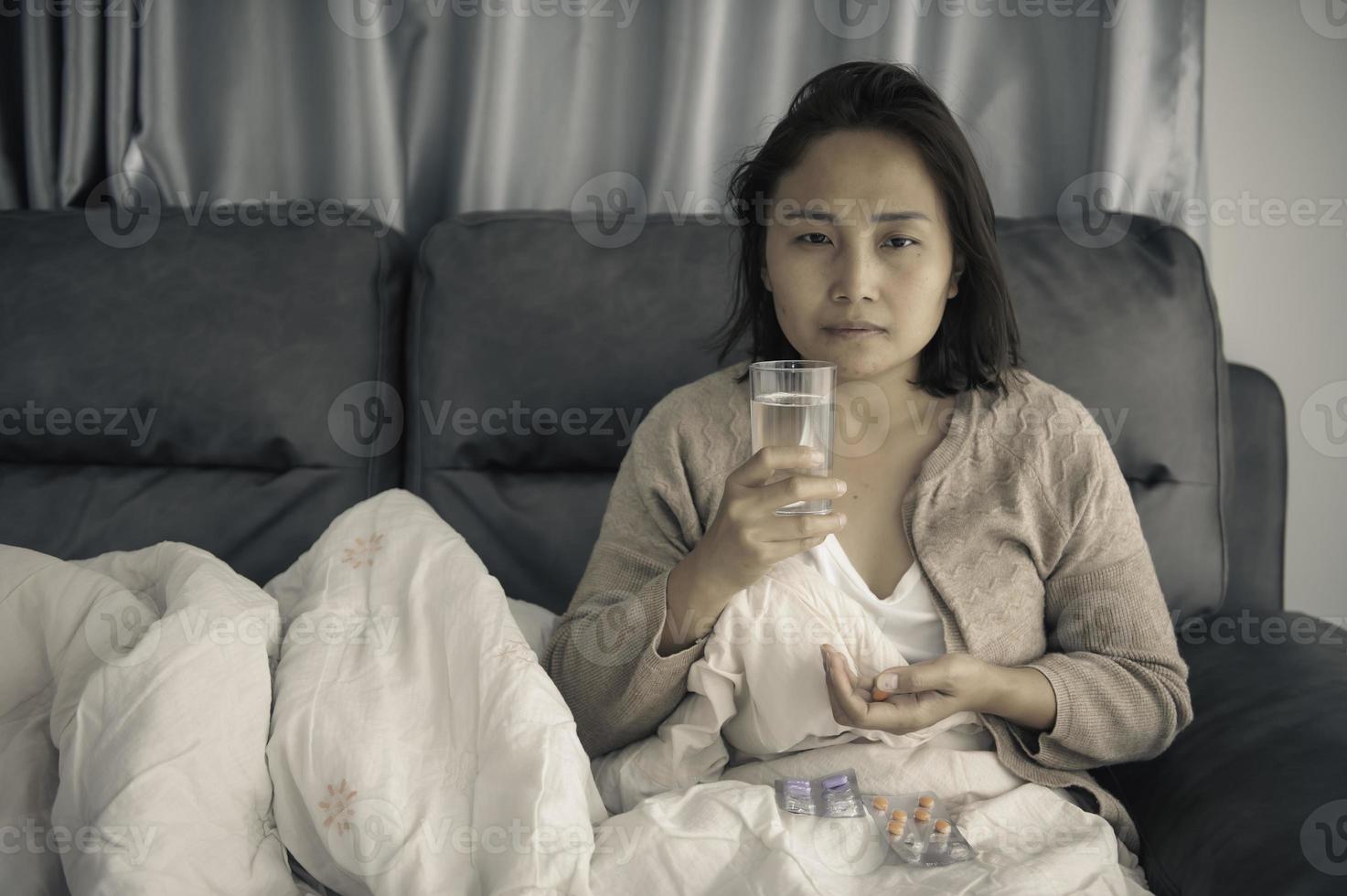 Asian sick woman sit on the sofa stay at home,The woman felt bad, wanted to lie down and rest,high fever photo