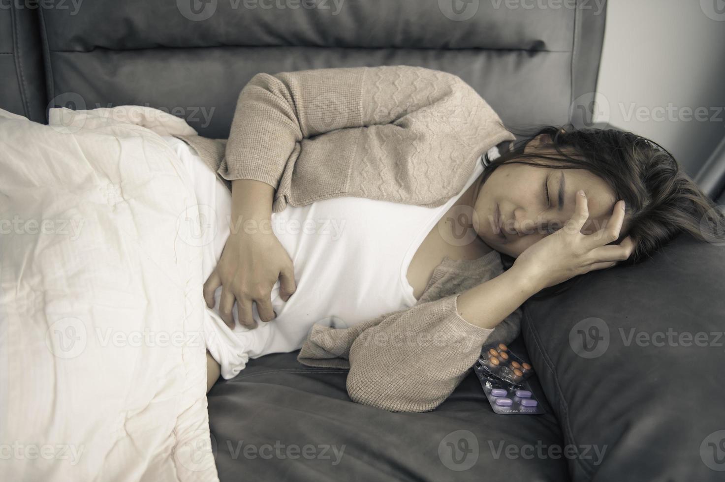 Asian sick woman sit on the sofa stay at home,The woman felt bad, wanted to lie down and rest,high fever photo