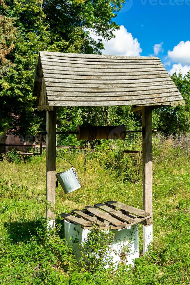 Old well with iron bucket on long forged chain for clean drinking water photo