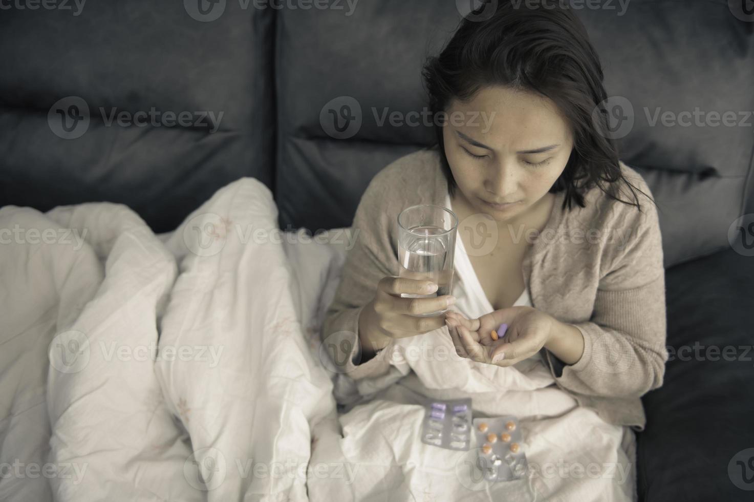 mujer asiática enferma sentada en el sofá, quédese en casa, la mujer se sintió mal, quería acostarse y descansar, fiebre alta foto