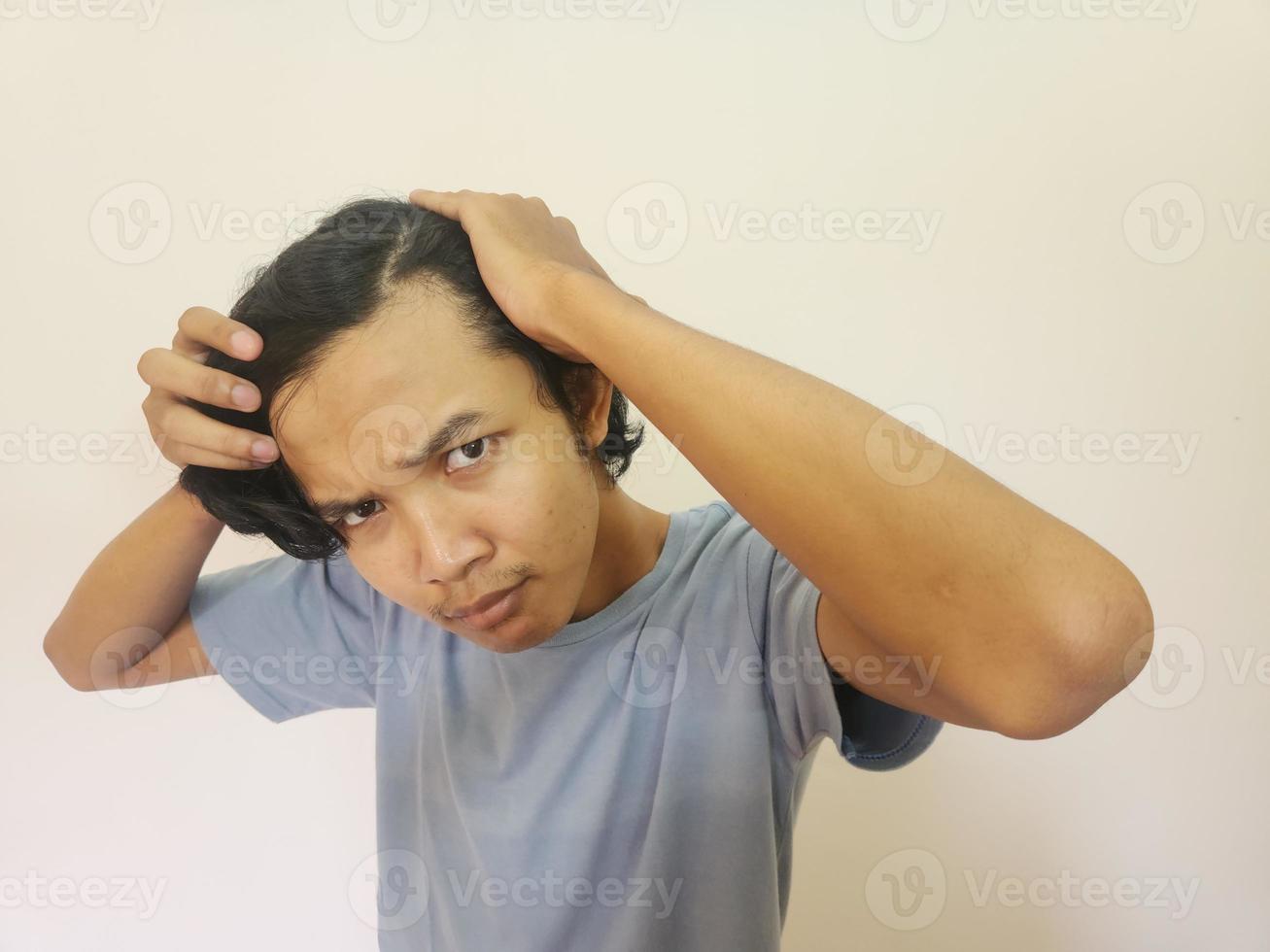 Shocked face of Asian man getting bald and lost hair in isolated white background photo