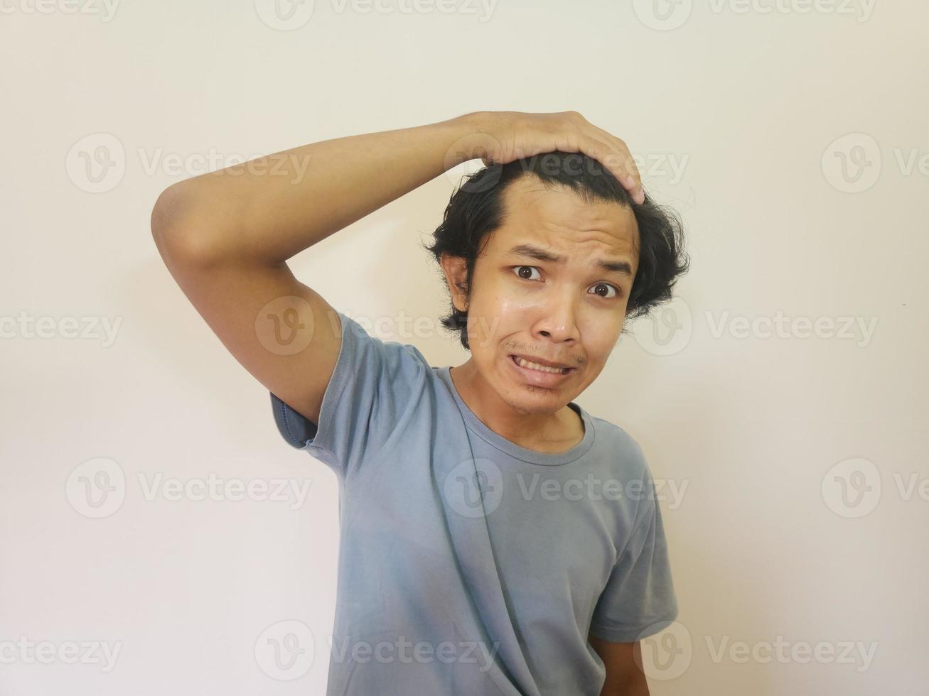 Shocked face of Asian man getting bald and lost hair in isolated white background photo