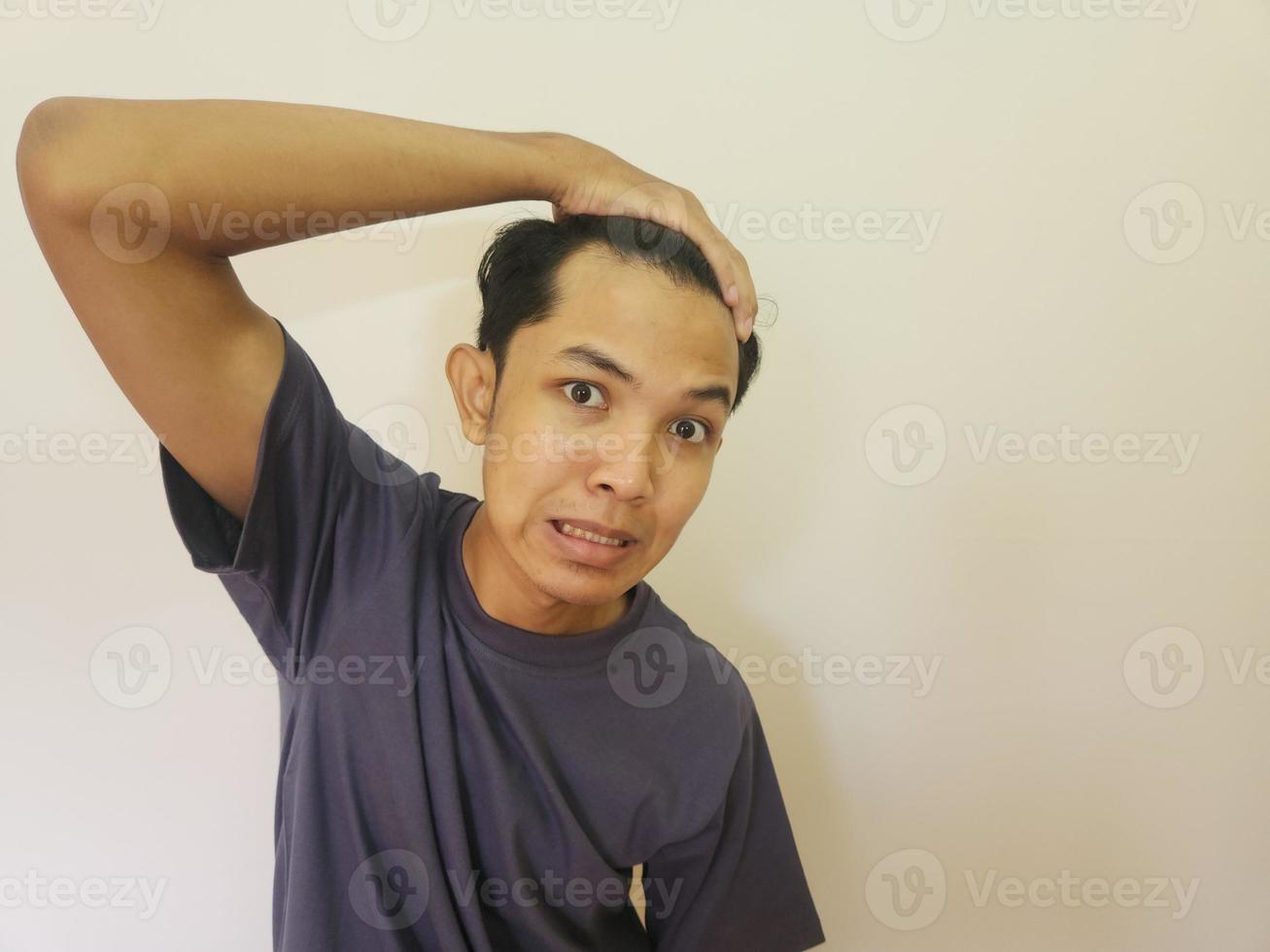 Shocked face of Asian man getting bald and lost hair in isolated white background photo