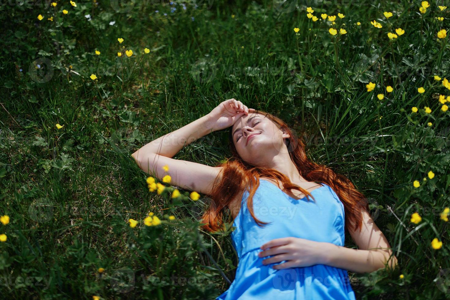 mujer sonrisa mentiras en el verde césped en el verano Dom con amarillo flores, felicidad, rojo largo pelo foto