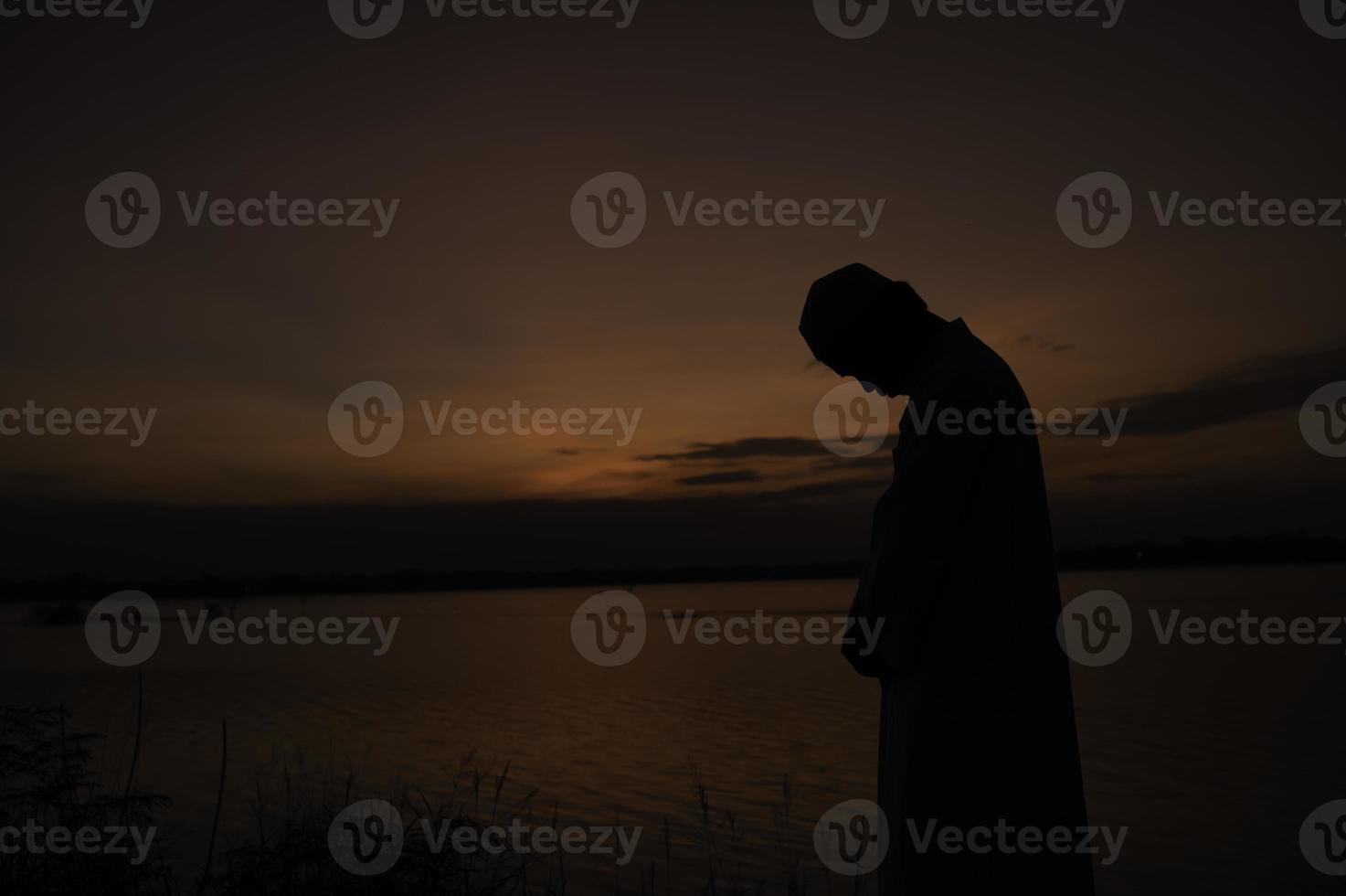 Silhouette Young asian muslim man praying on sunset,Ramadan festival concept photo