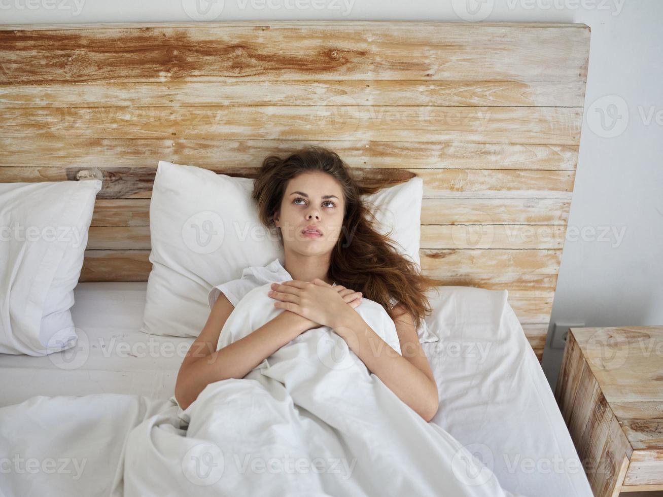 woman lying in bed under the blanket emotions look up photo