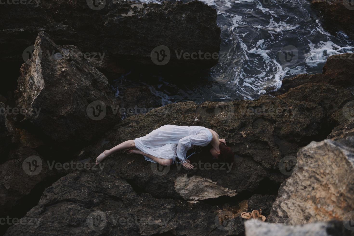woman in a white dress lying on a stone in a white dress unaltered photo