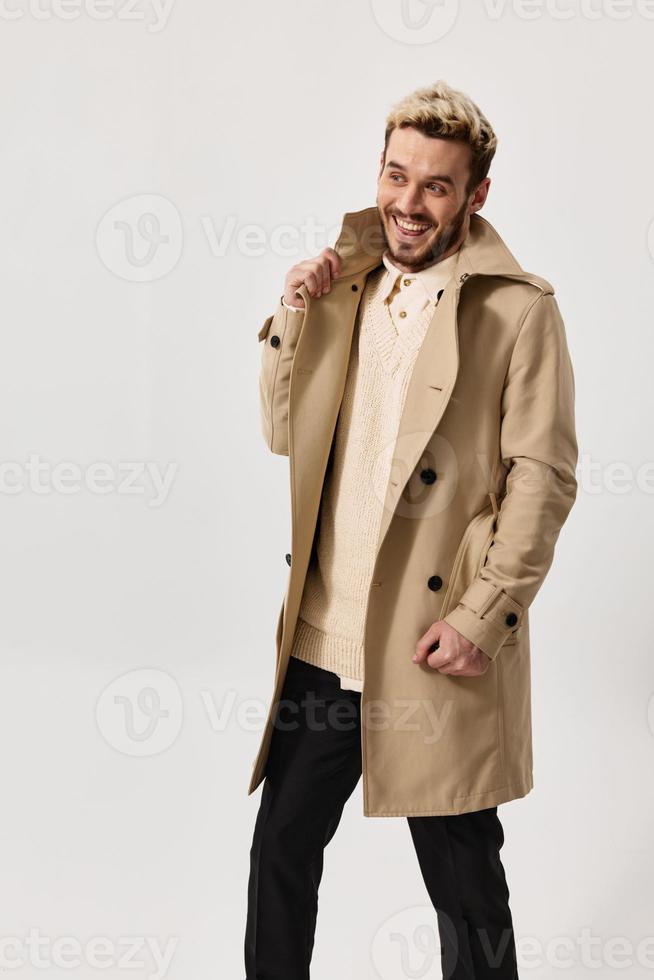 a man in a coat on a light background dark trousers sweater model portrait photo