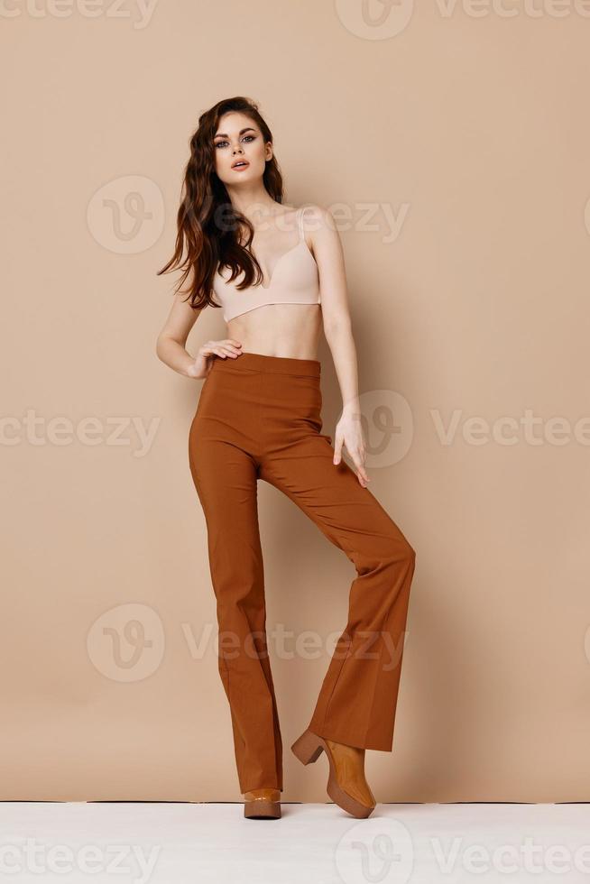 pretty woman in pants and bra on beige background red hair boots model photo