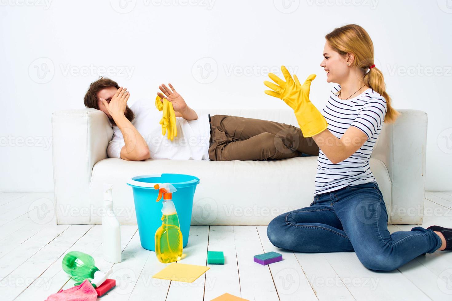 The wife cleans up while the husband lies on the couch interior housework photo